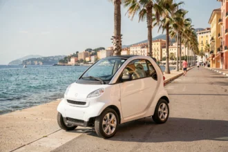 Voiture sans permis blanche garée sur la Promenade des Anglais à Nice avec vue sur la mer Méditerranée