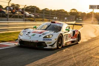 Voiture de GT d'endurance prise en virage sur un circuit au soleil couchant